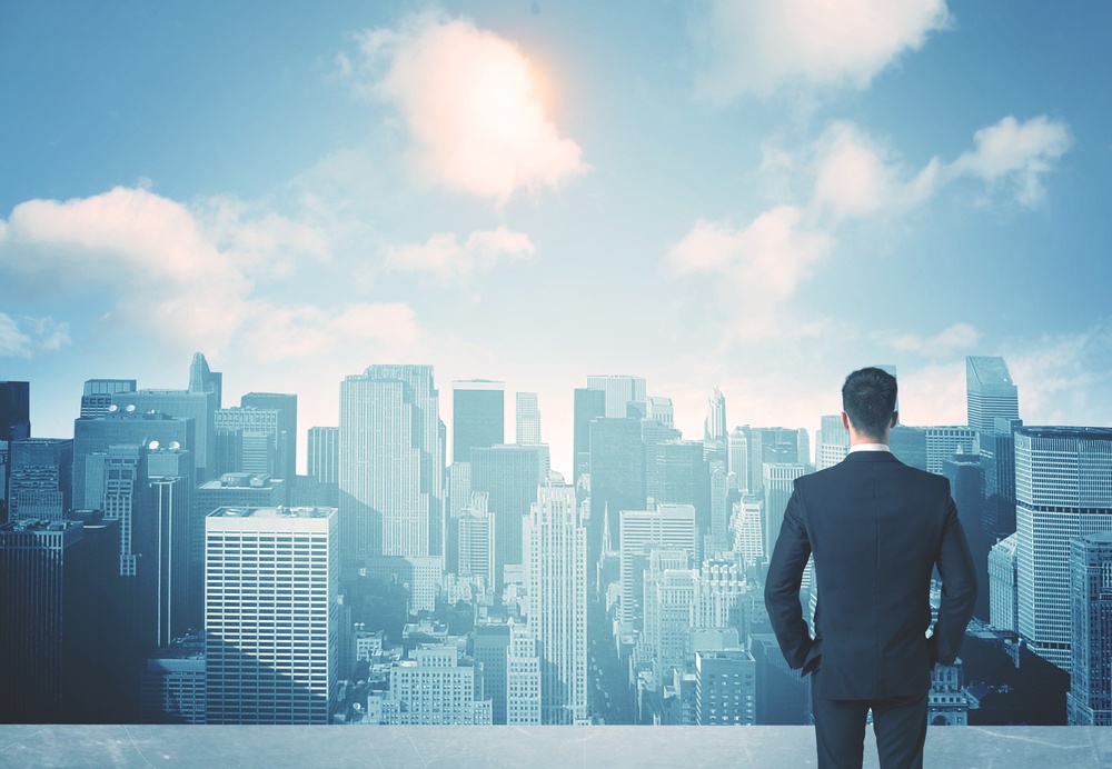 Businessman standing on a roof and looking at future city.jpeg