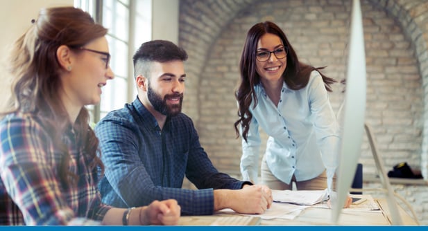 Smiling colleagues looking at SAP Business One reports on a computer